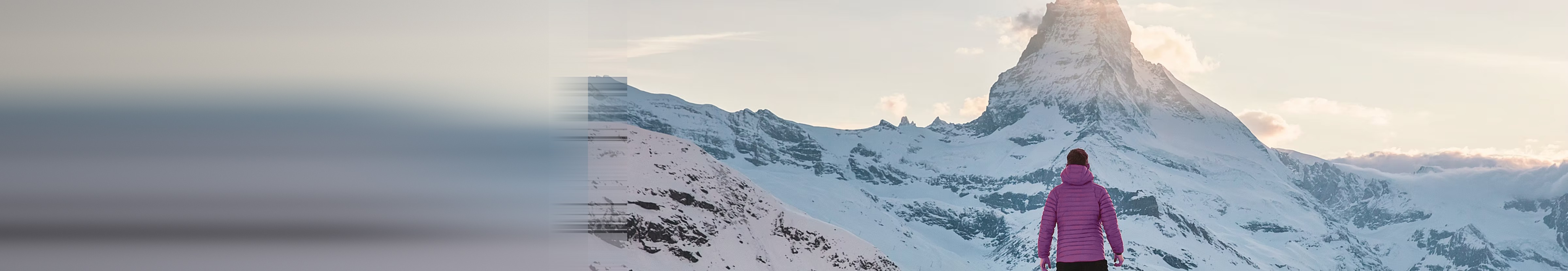 Traveller in a violet puffer jacket looking up at a snow-capped mountain peak at dawn — PCL IT brand photography